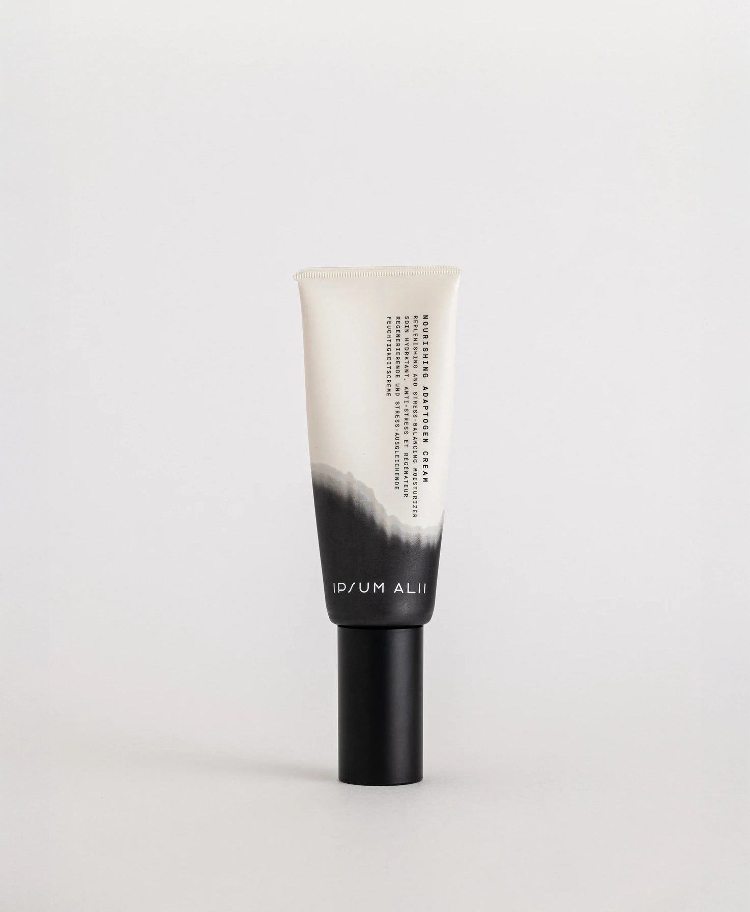 A single tube of Ipsum Ali Nourishing Adaptogen Cream standing upright against a plain light background. The packaging is white with a black gradient design and a black cap.