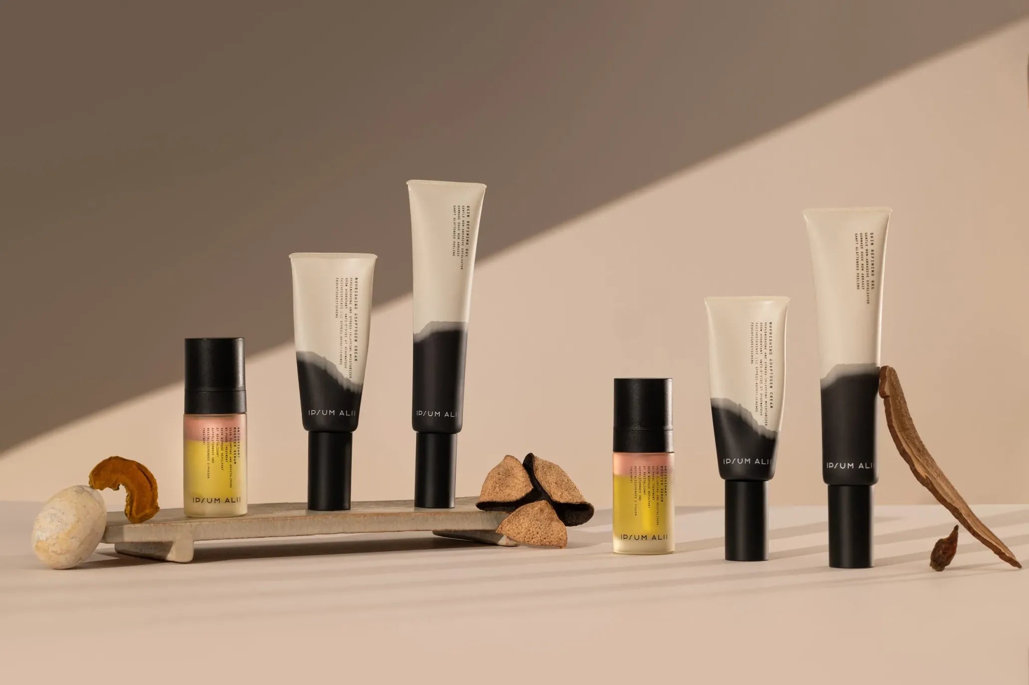 A curated display of Ipsum Alii skincare products, including serums and refining gels, arranged on a beige surface with natural ingredients like dried roots and mushrooms under warm sunlight.