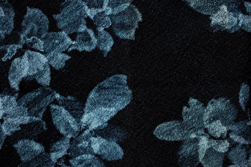 A piece of kimono fabric featuring an intricate, woven floral pattern in varying shades of blue.