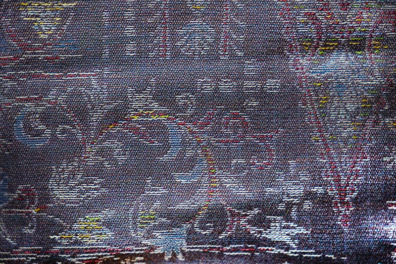 A piece of kimono fabric featuring an intricate, woven geometric pattern in varying shades of purple.