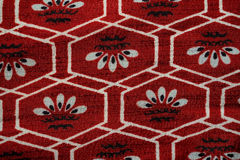 A piece of kimono fabric featuring an intricate, woven geometric pattern in varying shades of red and white.