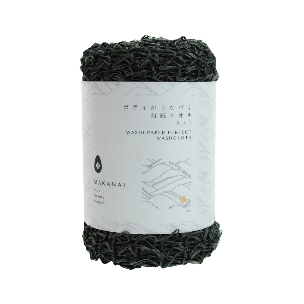 A rolled dark green Makanai Washi Paper Perfect Washcloth with a white paper label wrapped around it. The label features minimalist text and design elements in black and gray.