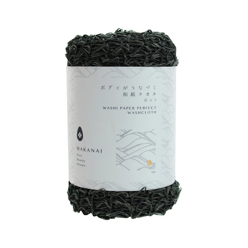 A rolled dark green Makanai Washi Paper Perfect Washcloth with a white paper label wrapped around it. The label features minimalist text and design elements in black and gray.
