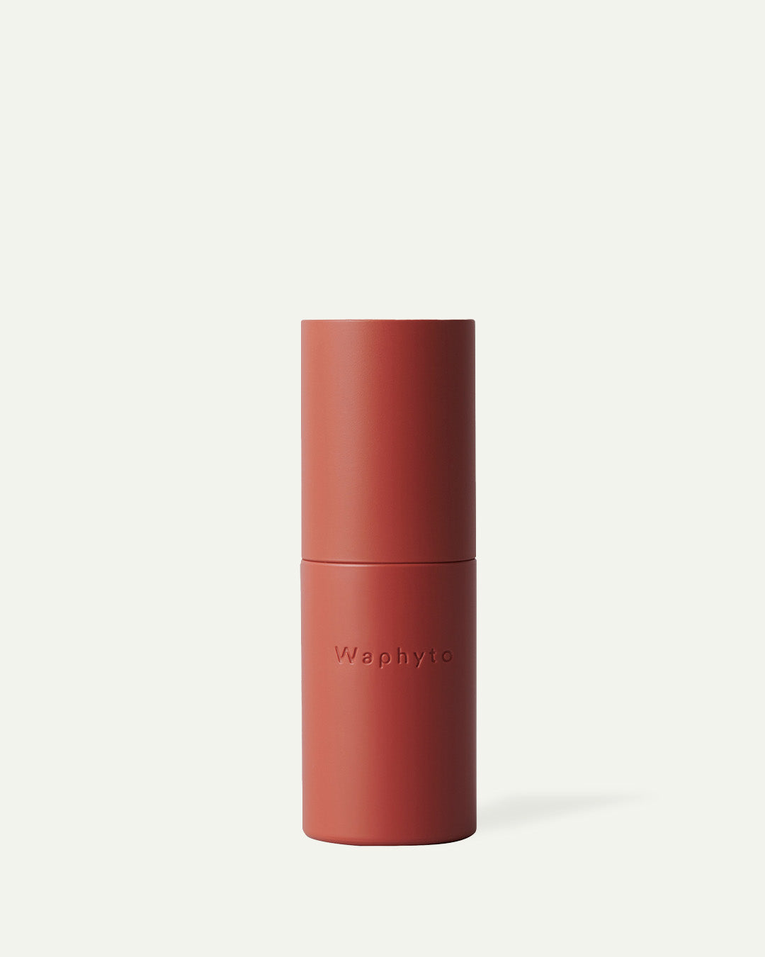 Red cylindrical skincare bottle with ‘Waphyto’ text on a light background.