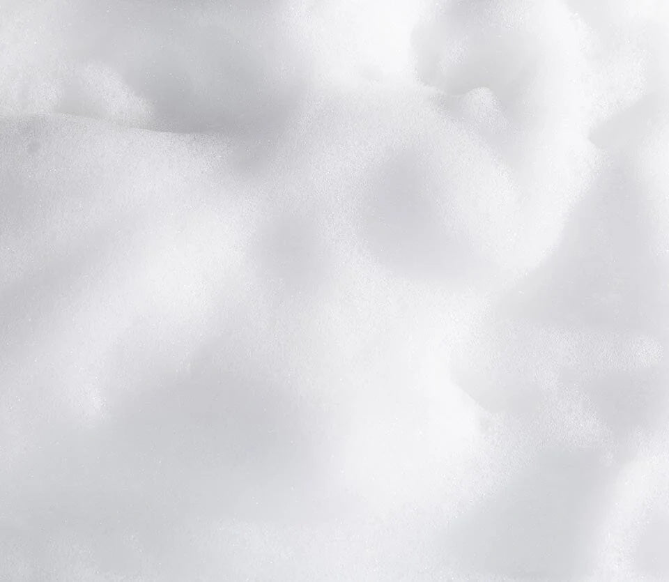 A close-up view of soft white foam with a smooth, airy texture. The lighting highlights the fluffy consistency, giving it a clean and fresh appearance.