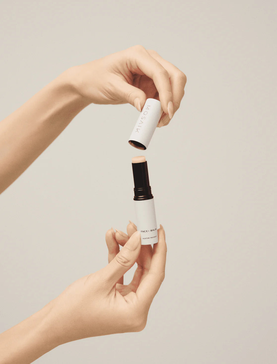 A person opens a tube of Mosaik Face Balm, revealing the product’s creamy stick formula. The minimalist packaging and soft lighting create an elegant, modern aesthetic.