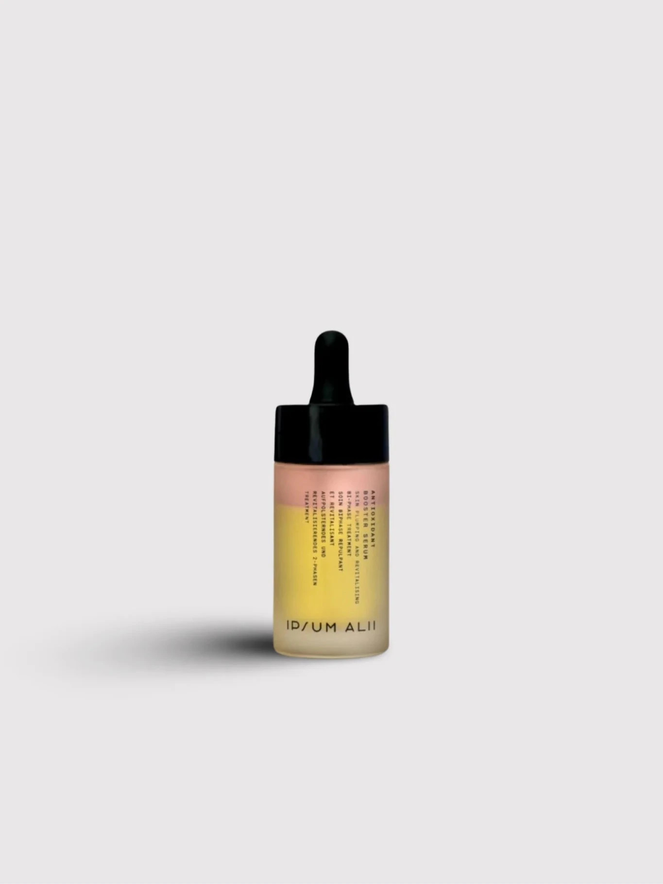 A bottle of Ipsum Ali facial oil with a black dropper cap standing against a plain light background. The bottle contains two visible layers of oil in pink and yellow tones.