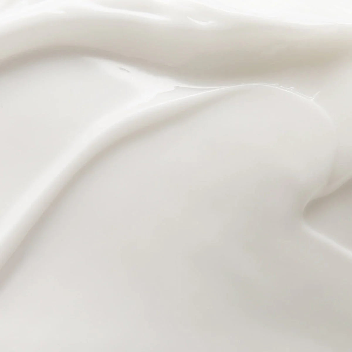 A close-up of a smooth white cream texture with soft light reflections. The image highlights the product’s silky consistency and glossy surface.